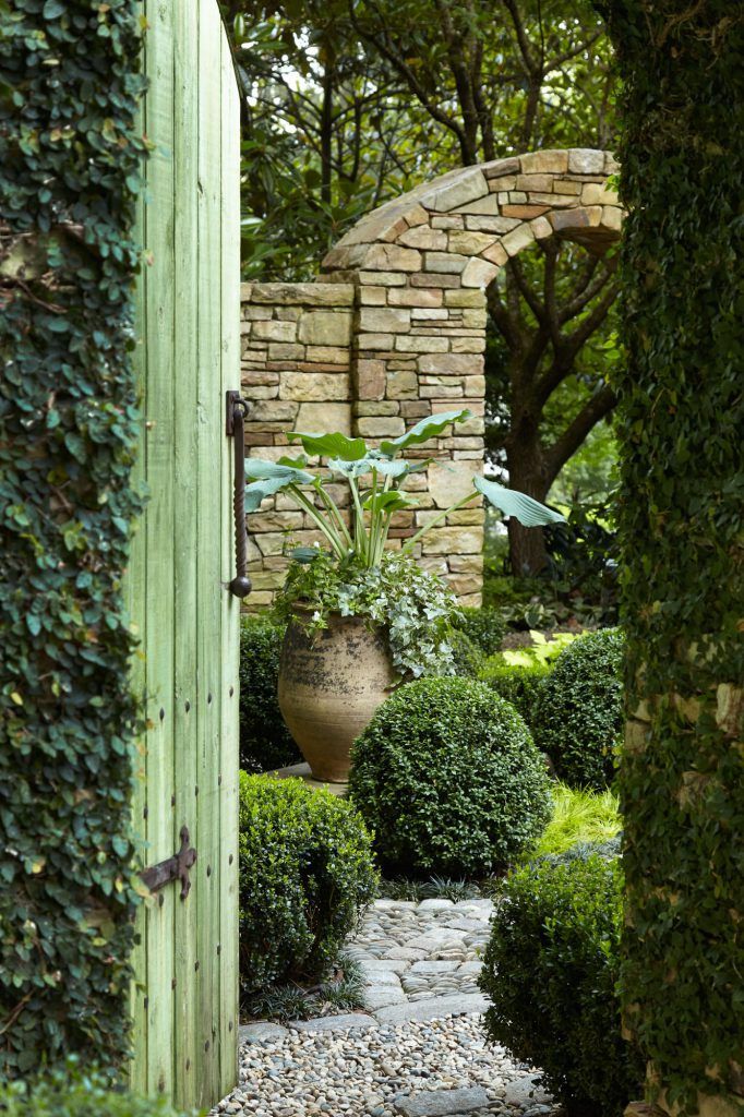 an open door leading into a garden with stone walkways and green plants on either side