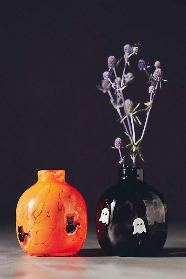 two black and orange vases with flowers in them