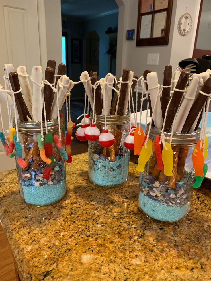 four jars filled with candy sticks on top of a counter