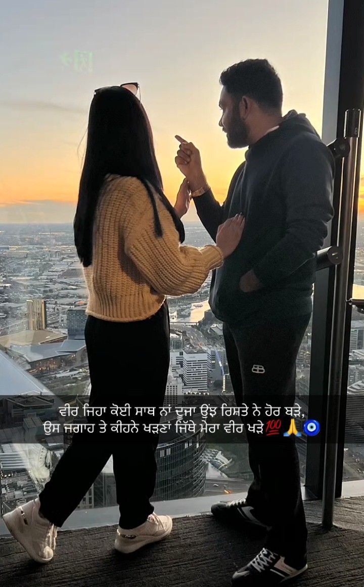 a man and woman standing in front of a window looking out at the cityscape