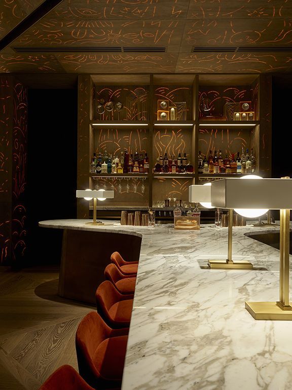 a bar with marble counter tops and red chairs