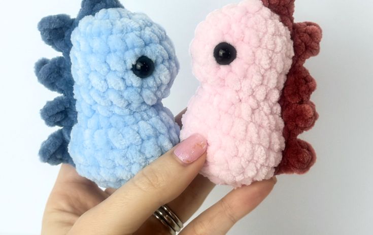 two crocheted seahorses are being held in their hands