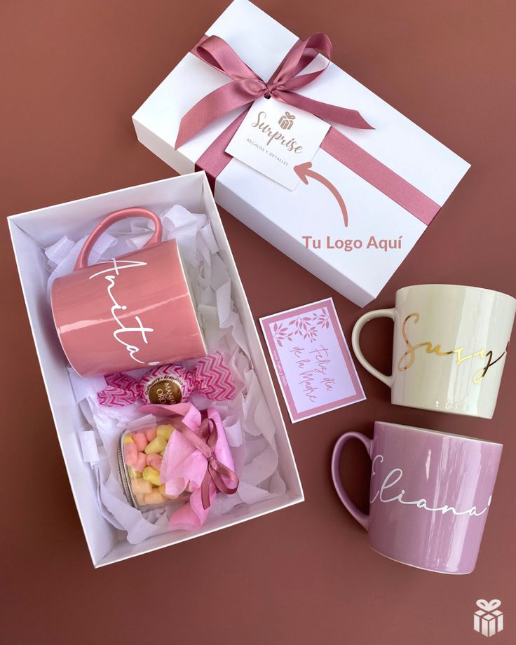 two pink coffee mugs in a gift box next to a white and pink cup