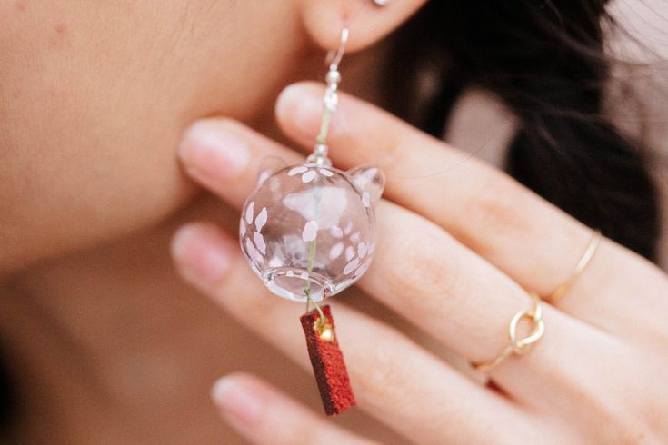 a close up of a person holding a cat earring in front of her face