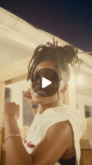 a woman with dreadlocks standing in front of a house