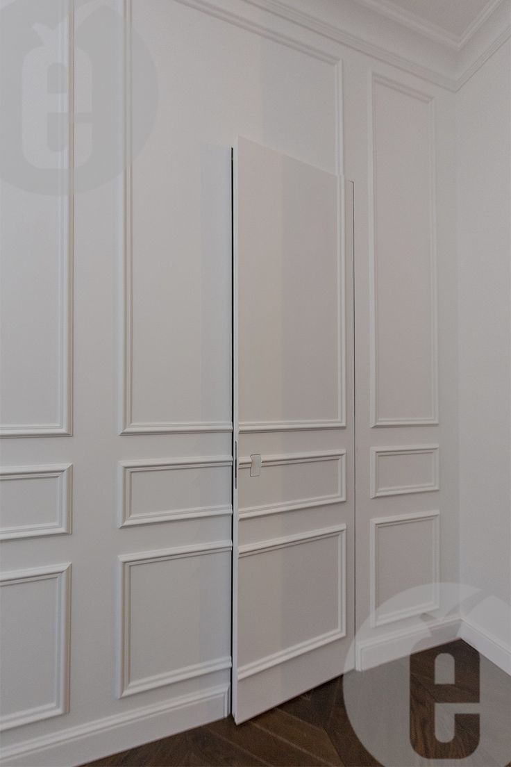 an empty room with white closets and wood flooring on the walls, in front of a mirror