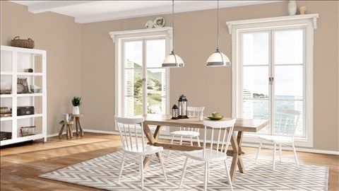 a dining room with yellow walls and white chairs around a table in front of two windows