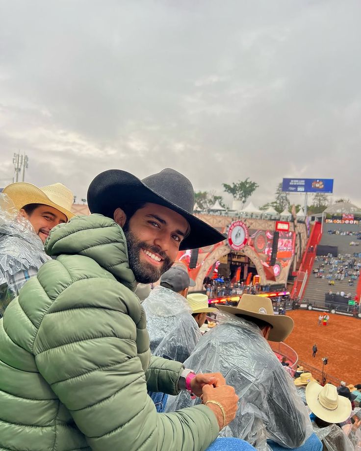 two men wearing hats and sitting in the stands at a sporting event on a cloudy day