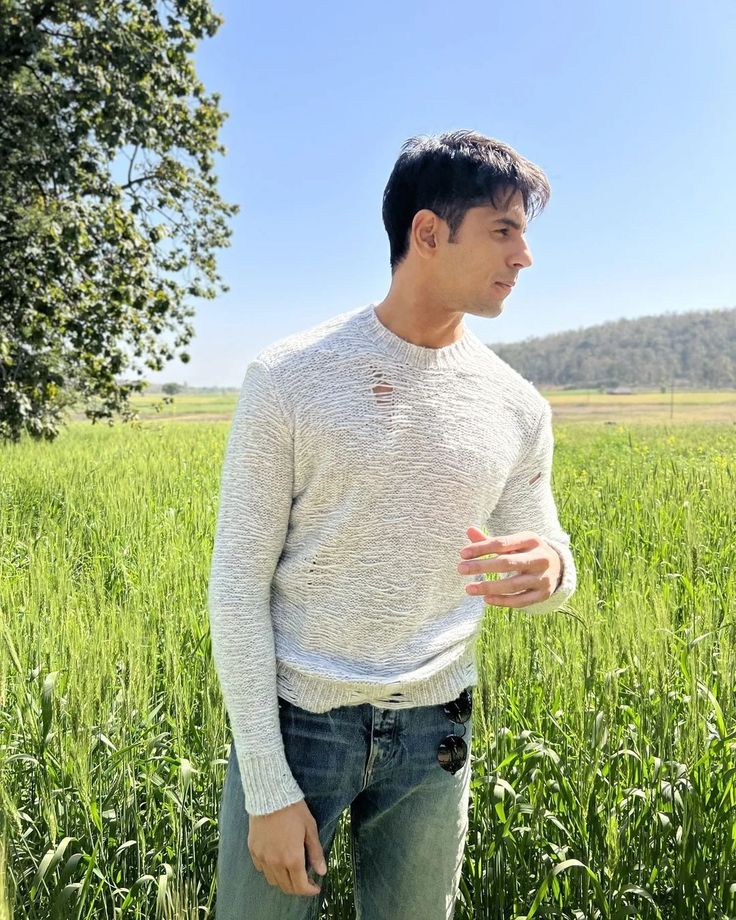 a man standing in the middle of a field with his hand out to someone else