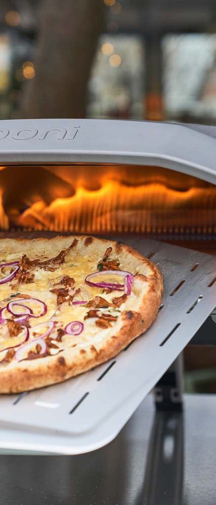 a pizza sitting on top of a white tray in front of an open fire oven