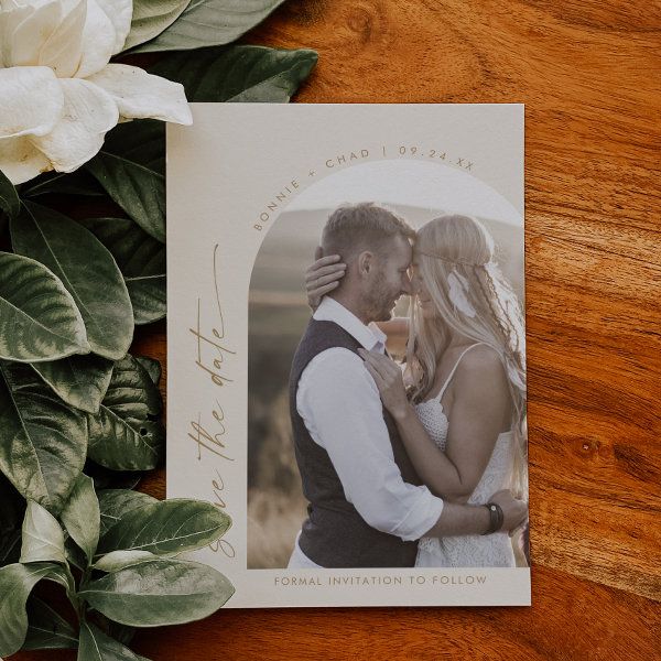 a wedding photo with flowers and greenery around it on top of a wooden table