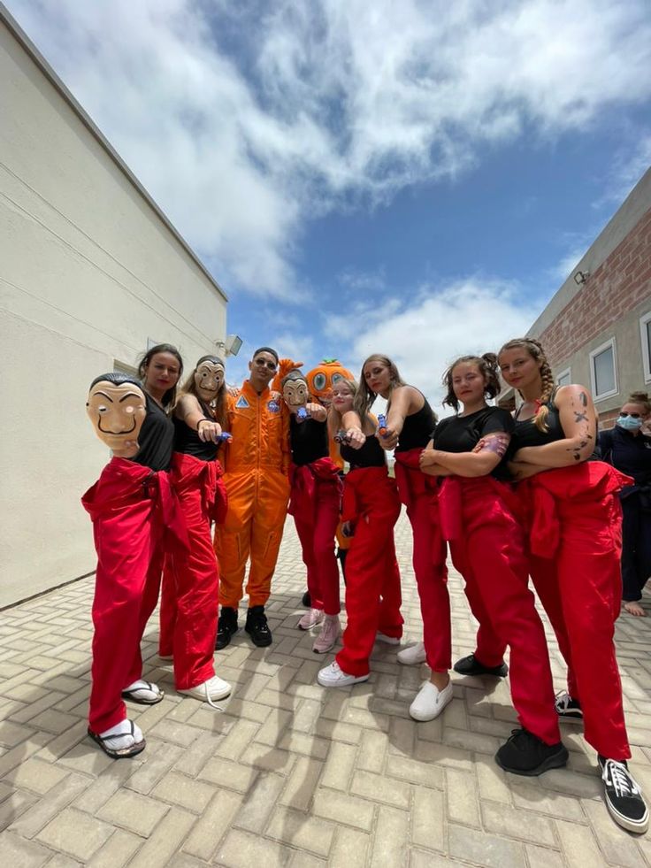 a group of people standing next to each other in front of a building wearing orange jumpsuits