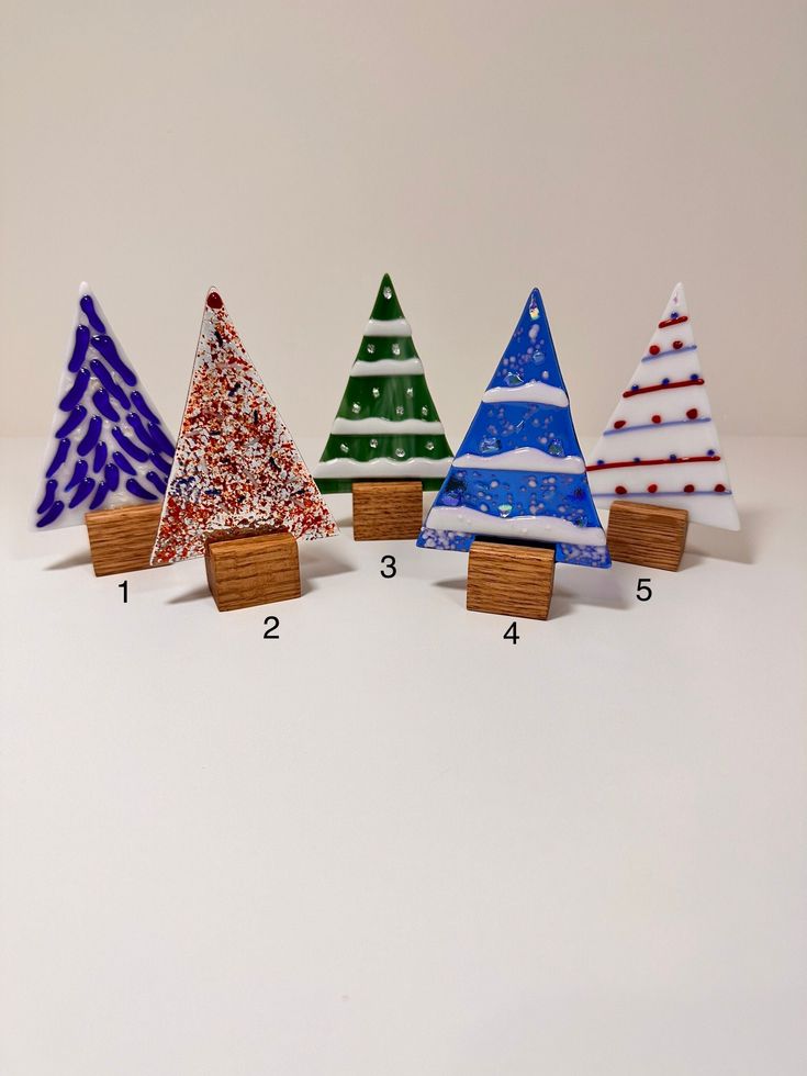 three small wooden christmas trees are lined up next to each other on a white surface