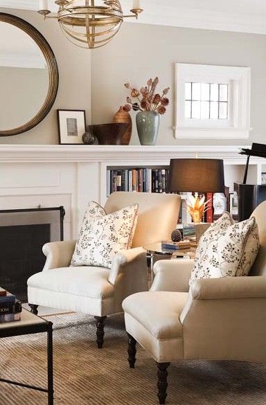 a living room filled with furniture and a fire place in front of a mirror on the wall