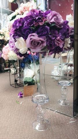 a vase filled with purple and white flowers sitting on top of a table next to a mirror