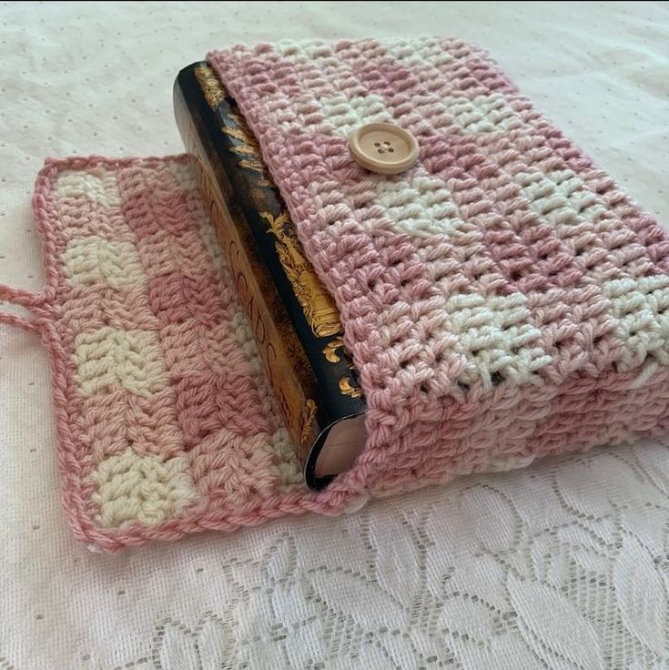 a pink and white crocheted purse with a button on it's side