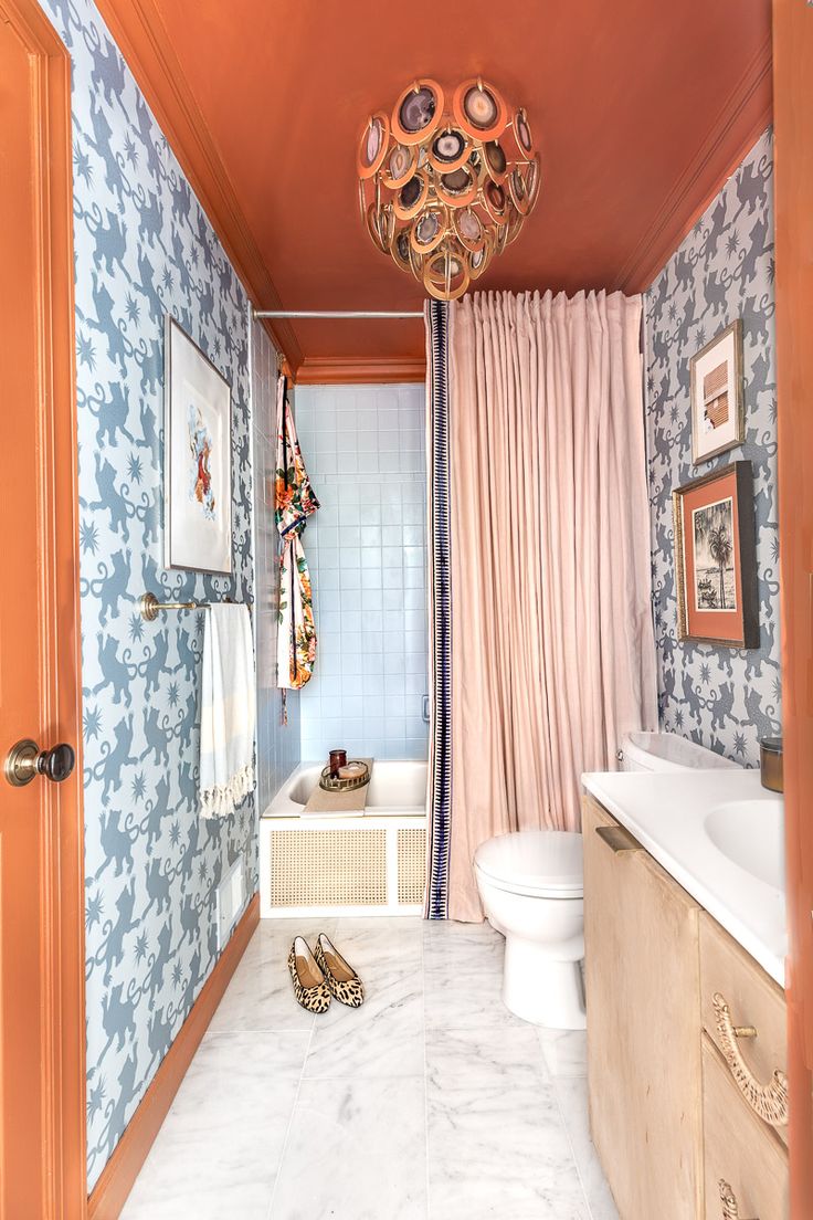 a bathroom with blue and orange wallpaper, white sink, toilet and bathtub