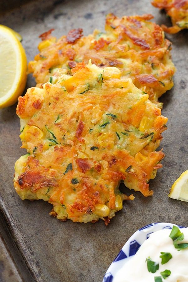 crab cakes with lemon wedges and sour cream on a baking sheet, ready to be eaten