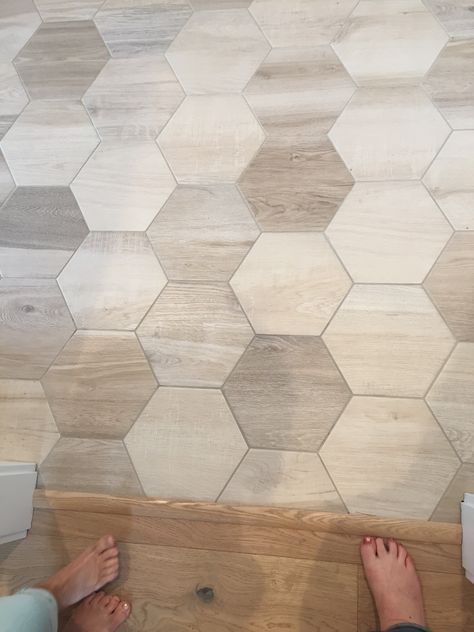 two people standing in front of a tiled wall with their feet up on the floor