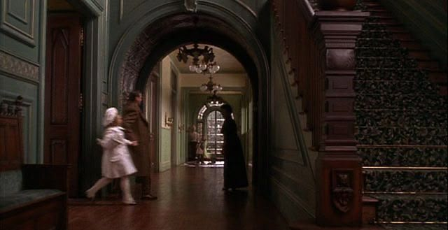 two people are walking down the hallway in an old house with green walls and wood floors