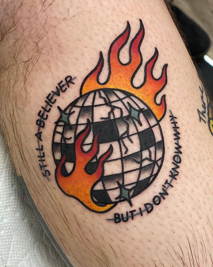 a man's thigh with a globe on fire and words written in black ink