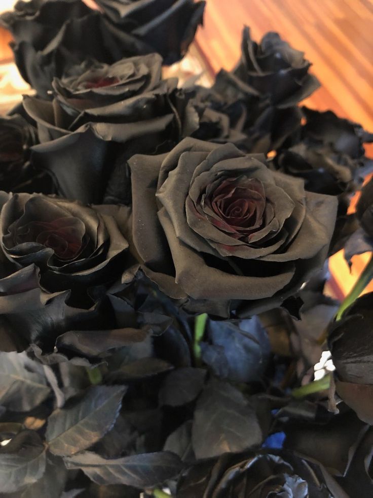 a bouquet of black roses sitting on top of a wooden table