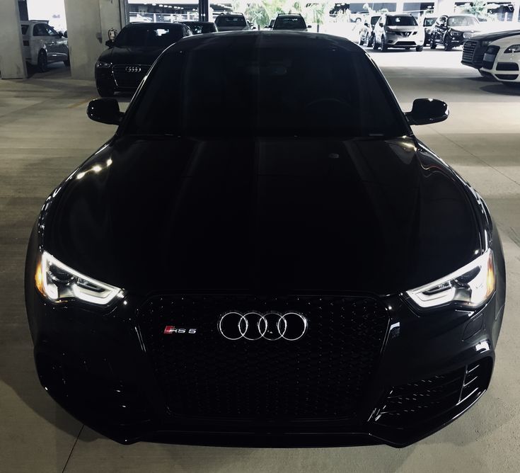 the front end of a black car in a showroom