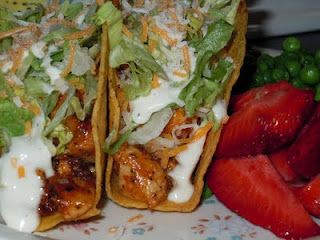 two tacos with chicken, lettuce and cheese on them next to strawberries