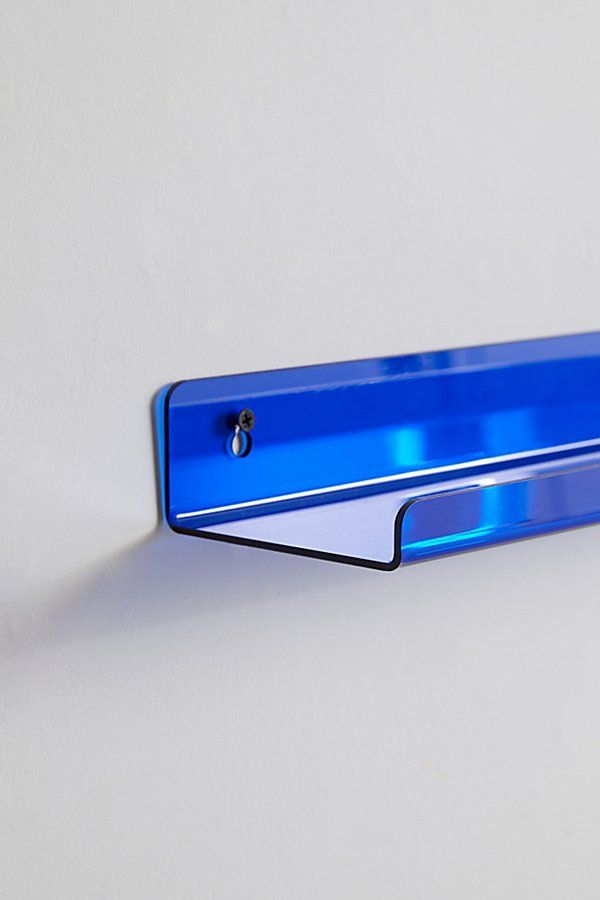 a blue metal object on a white wall with the light reflecting off it's side