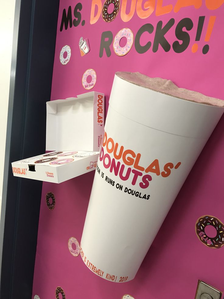 a paper cup with doughnuts on it is in front of a pink wall