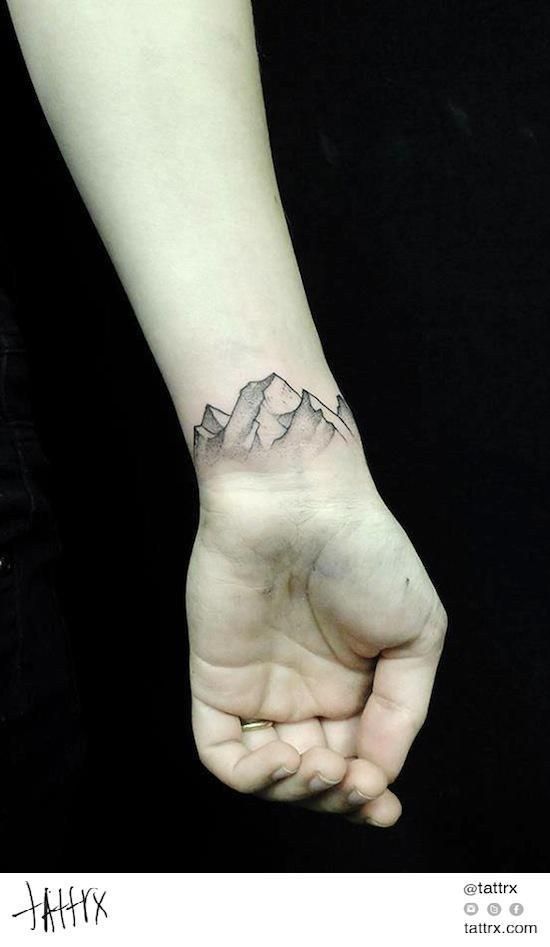 a hand with a mountain tattoo on it