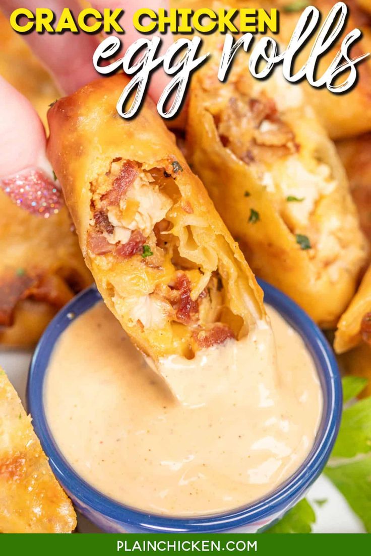 a hand dipping some chicken egg rolls into a small blue bowl with ranch dressing on the side