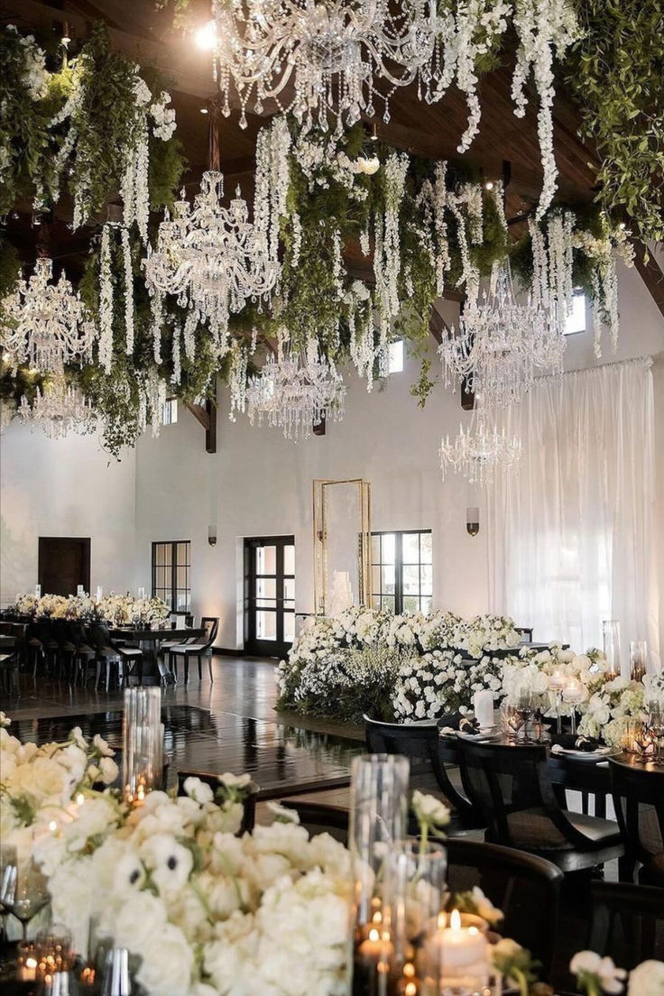 an elegant wedding reception with chandeliers and floral centerpieces in the ceiling