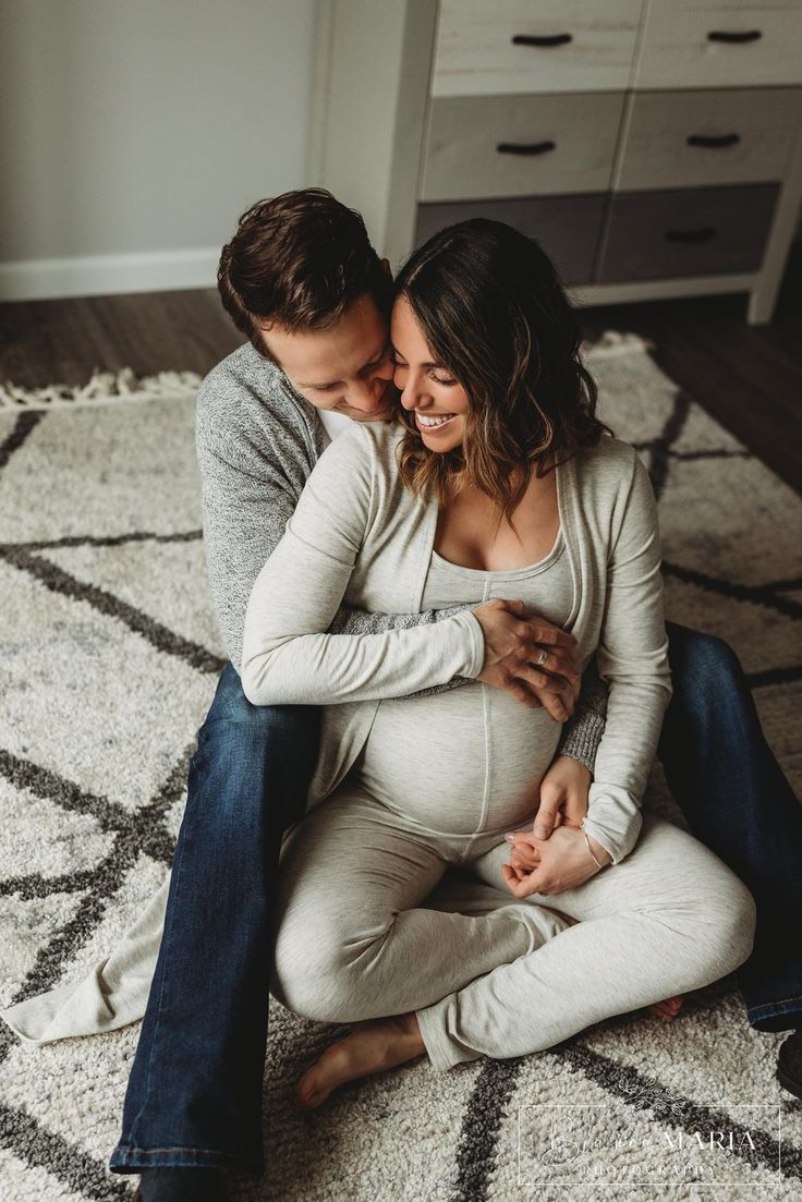 a pregnant couple cuddling on the floor