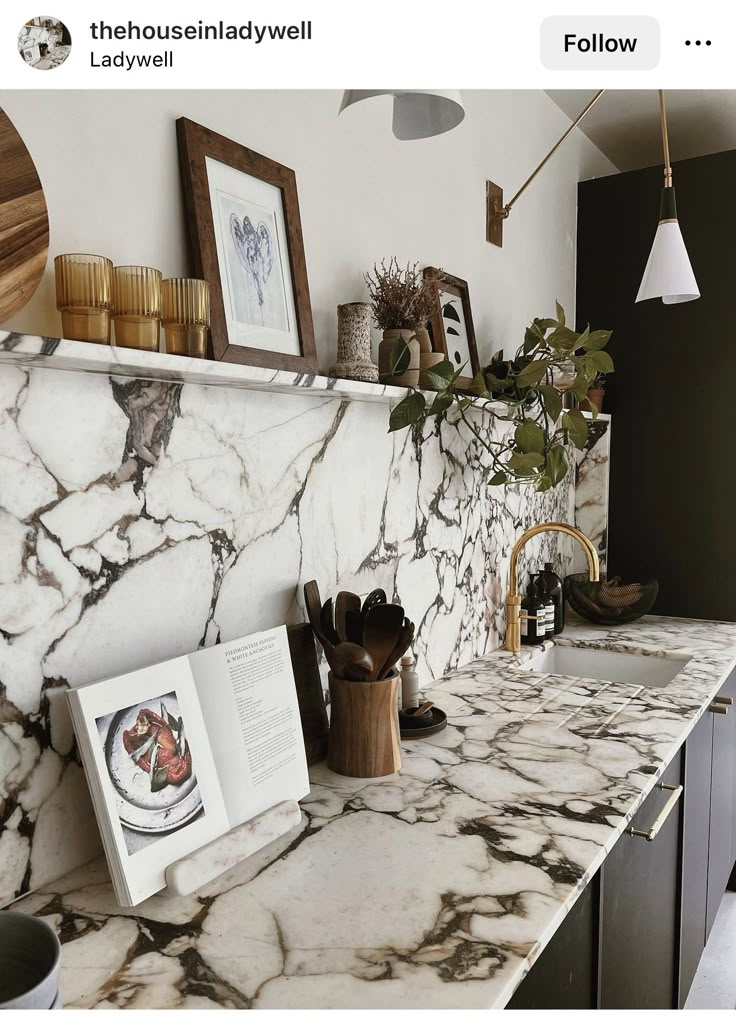 a marble counter top in a kitchen with pictures on the wall above it and an open book