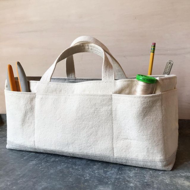 a white bag with two pencils, scissors and a toothbrush holder in it