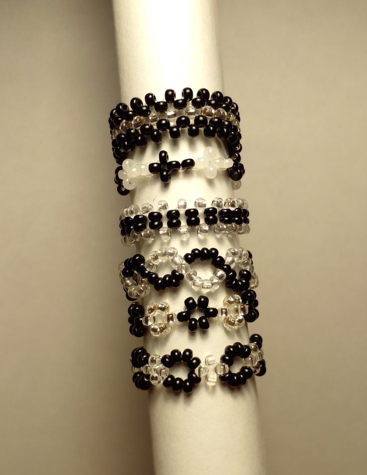 a stack of black and white beaded bracelets sitting on top of a white pole