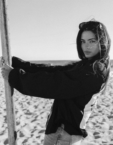 a woman standing on the beach holding onto a pole