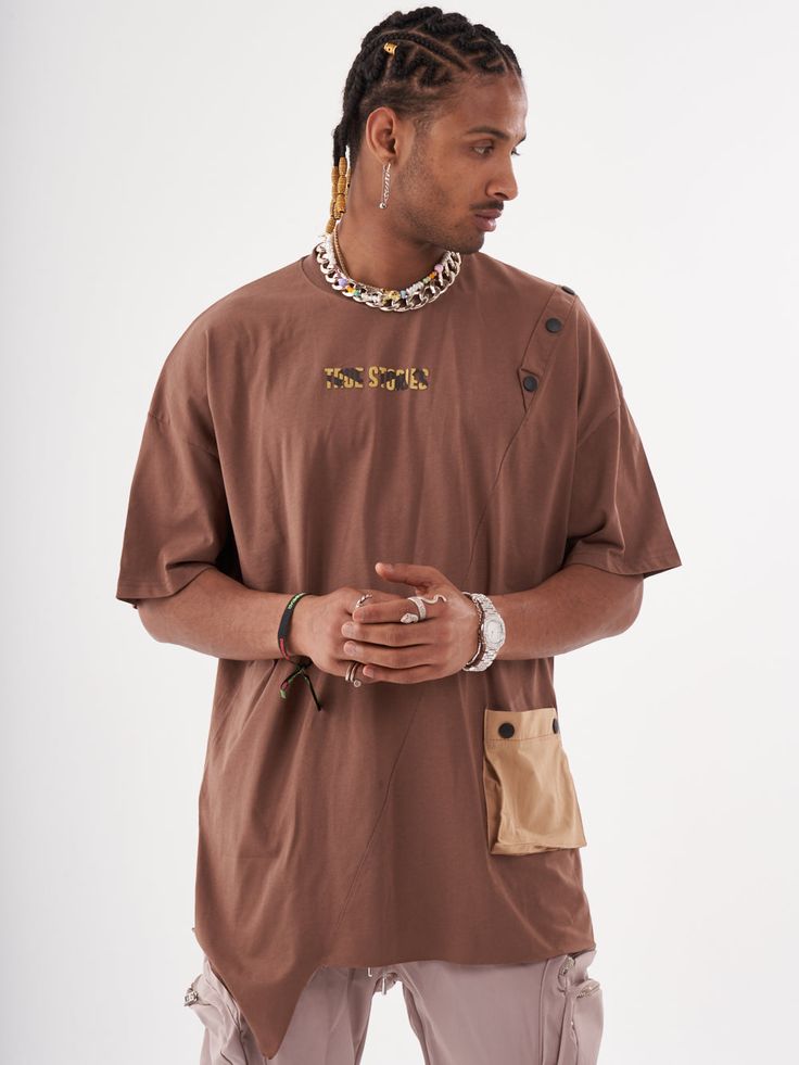 This coffee colored baggy T-shirt is the perfect addition to any beatnik's wardrobe! The button design and the asymmetrical hem gives it a stylish edge. The pocket is both functional and stylish, making this T-shirt a must-have for any fashion-savvy individual. FEATURES- Regular Cut- Smooth Feel- Comfort Fit- 95% cotton, 5% lycra SIZE RECOMMENDATIONModel is a regular size Large and he is wearing size Large Relaxed Fit Brown T-shirt With Pockets, Brown T-shirt For Fall Streetwear, Brown Cotton T-shirt With Pockets, Oversized Brown Tops With Pockets, Brown Tops With Pockets For Streetwear, Casual Brown Tops With Side Pockets, Brown Crew Neck Urban Top, Brown Urban Crew Neck Top, Urban Brown Crew Neck Top