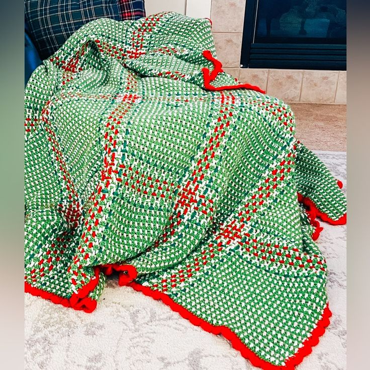 a green and red blanket sitting on top of a couch