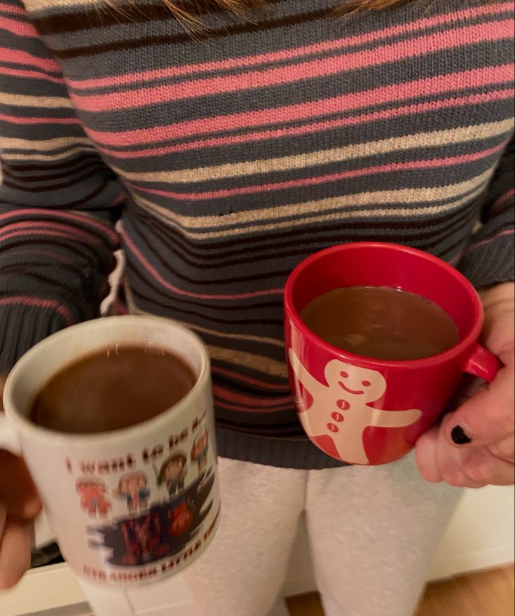 a woman holding two cups of hot chocolate