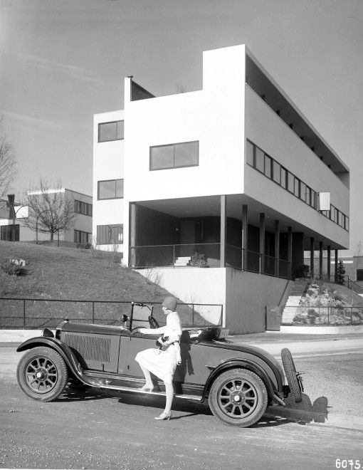 an old black and white photo of a woman sitting on the back of a car