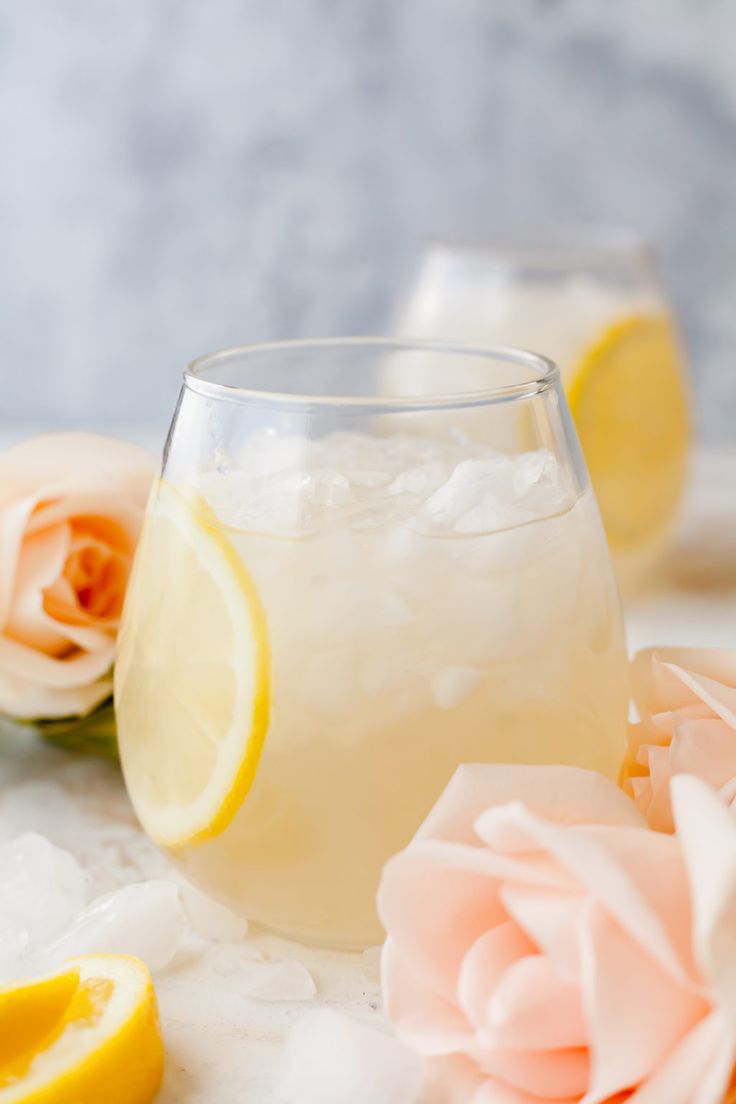 a glass filled with lemonade next to flowers