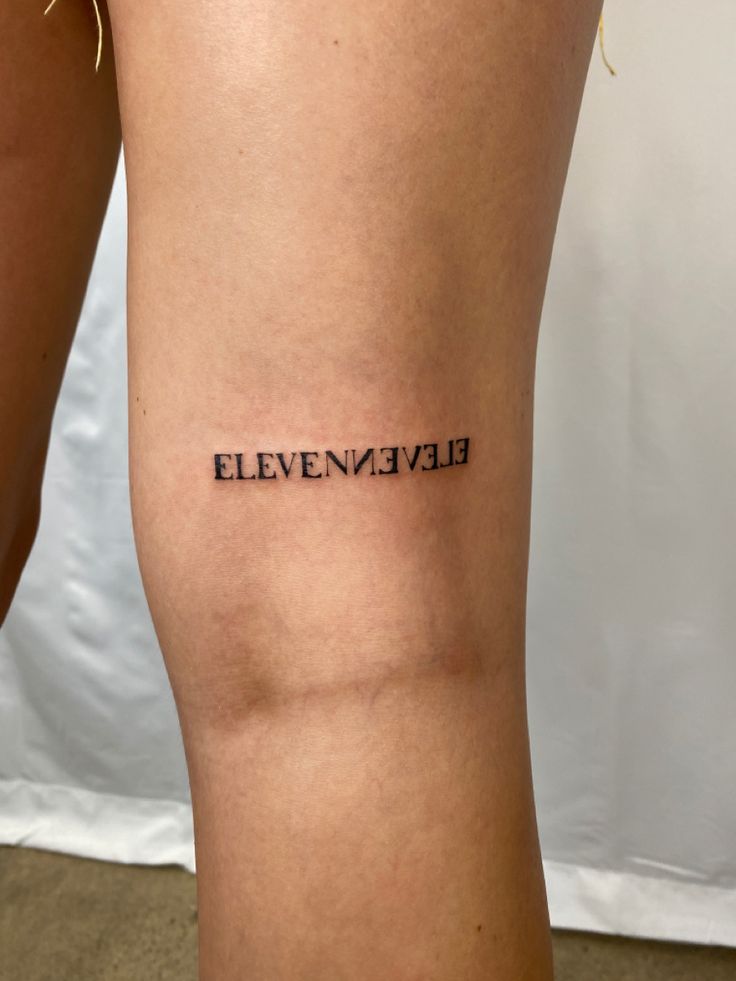 a woman's leg with the word eleven eleven written on it, in black ink