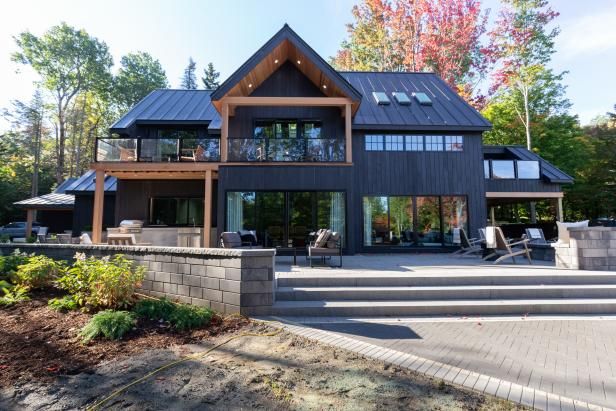 a large house sitting on top of a lush green hillside next to a wooded forest