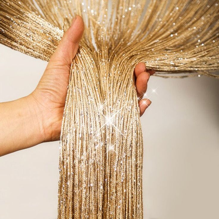 a hand is holding the top part of a gold sequined dress with fringes on it