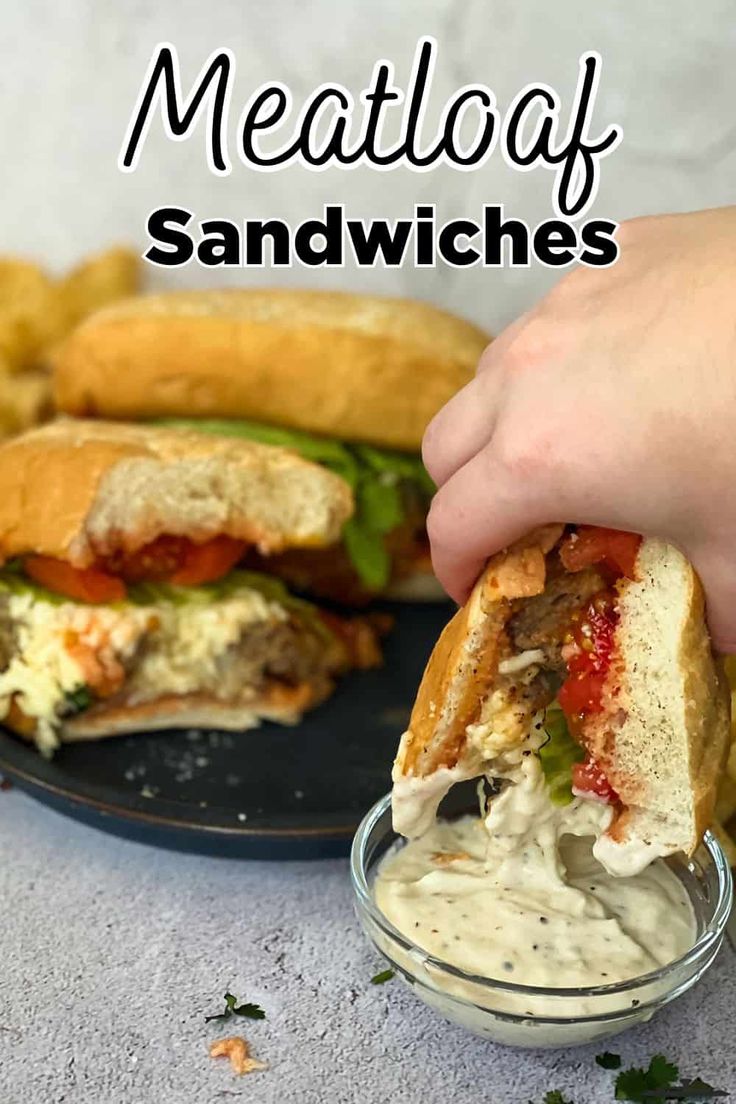 a hand holding a sandwich over a plate with some fries on it and the words meatloaf sandwiches