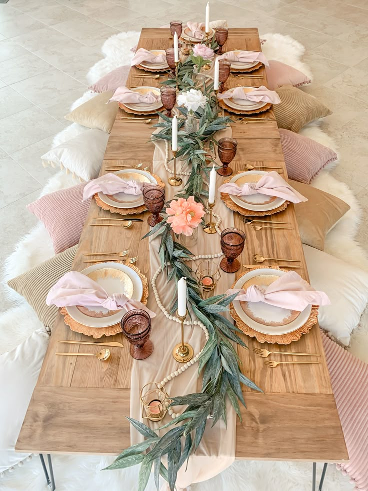 the table is set with pink and gold plates, napkins, candles, and flowers