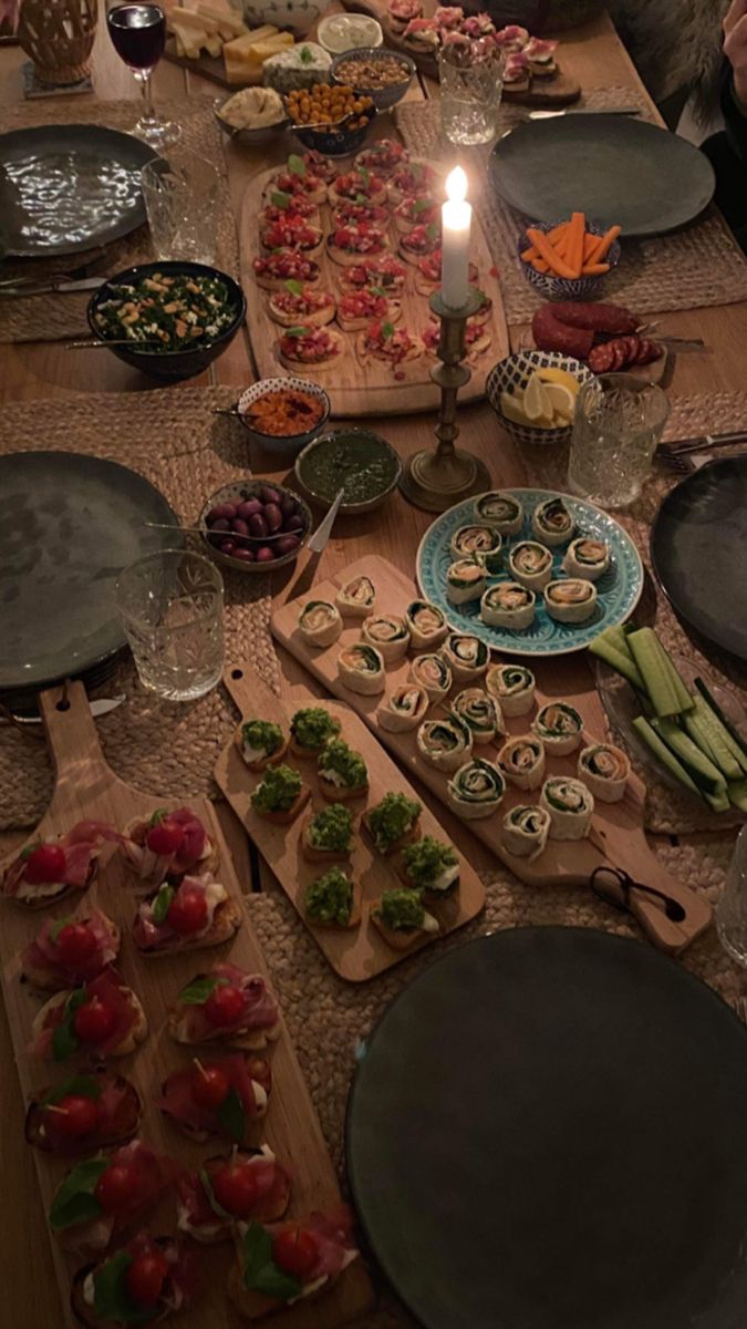 a long table filled with plates and bowls full of food next to a lit candle