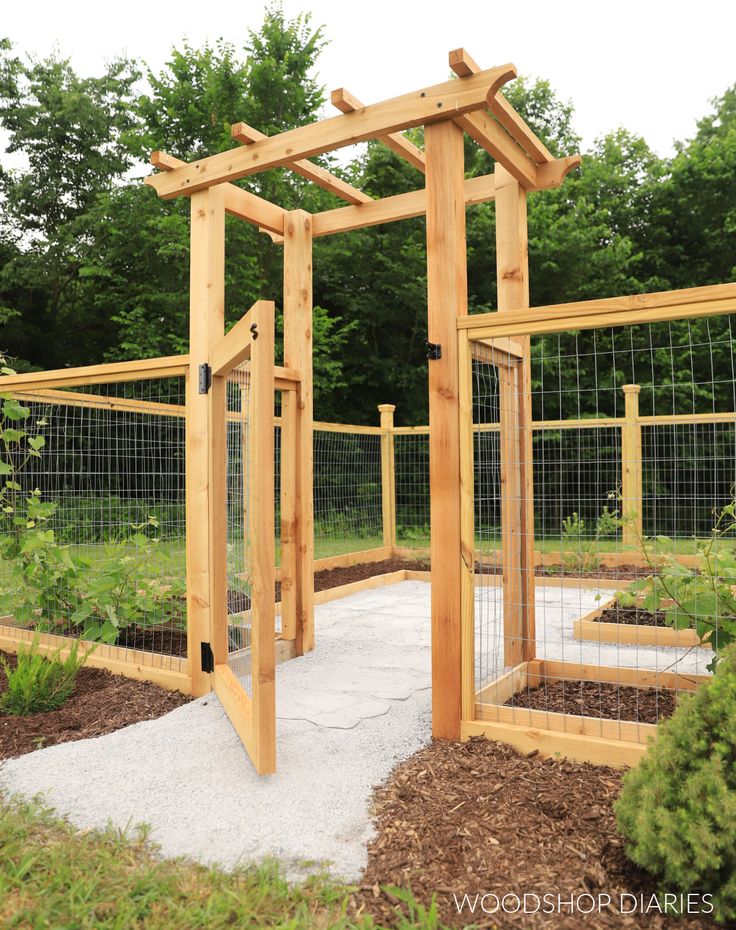 a wooden gated in area with plants and dirt on the ground next to it